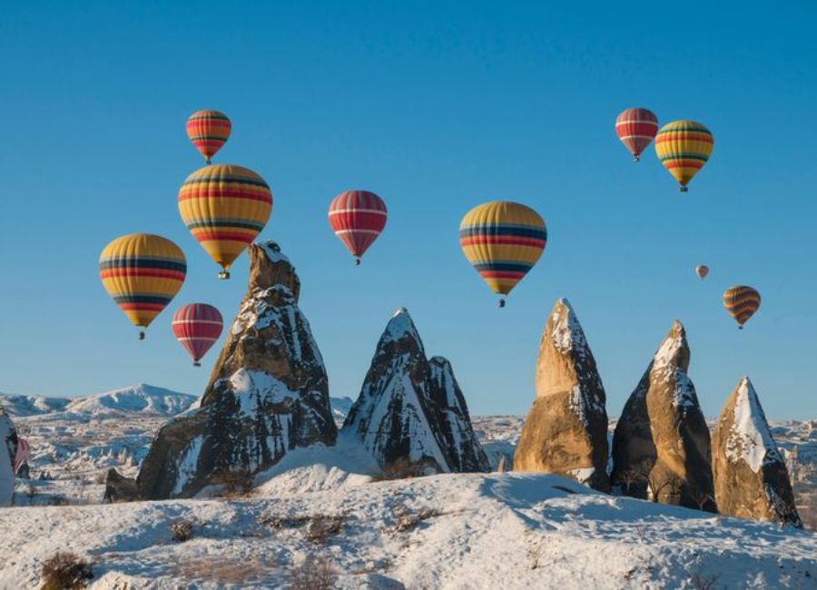 Hot air balloons flying over snowy Cappadocia in winter