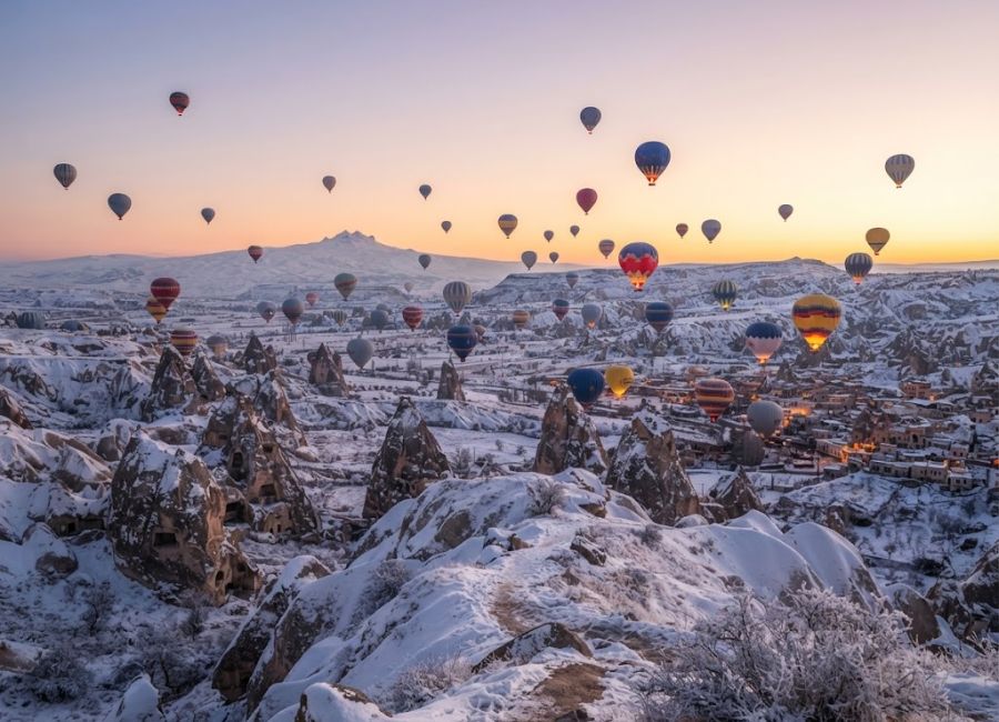 Hot air balloons flying over snowy Cappadocia in winter